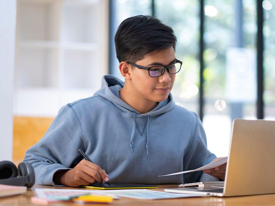 Duales-Studium bei ECOVIS KSO junger Mann mit Brille am Laptop mit Stift und Papier